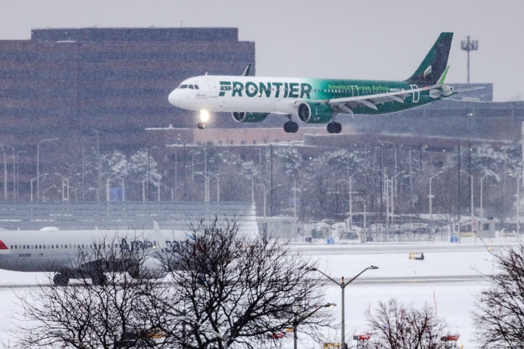 A Frontier plane flies above the tarmac