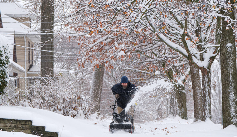 Justin Johnson uses a snowblower outside on a snowy sidewalk