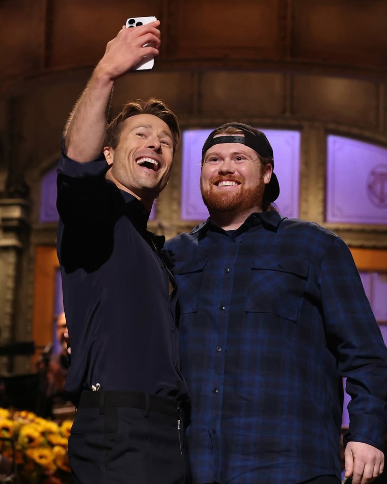 Glen Powell e Mitch, o motorista da UPS, posando para uma selfie quatro anos depois.