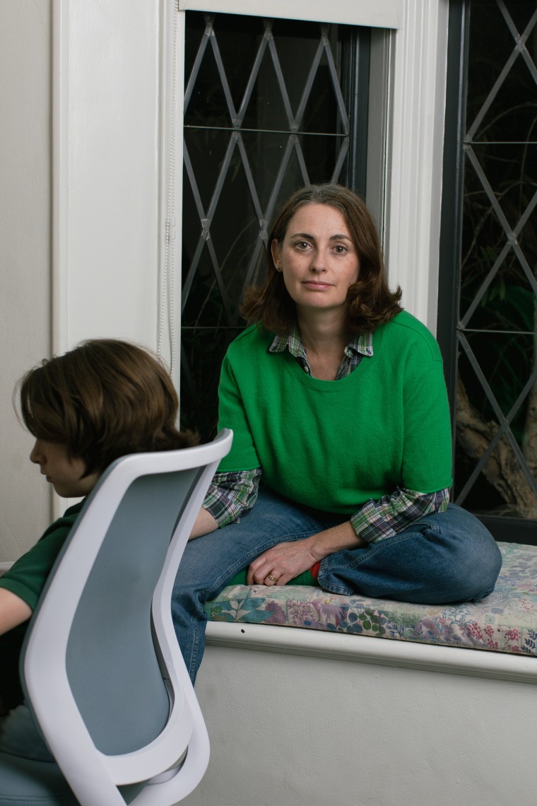 Lila sits next to her son, sitting in a computer chair.