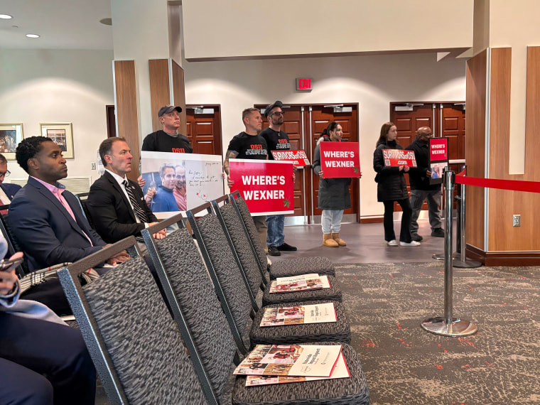 Protesters hold signs at the Ohio State University board of trustees meeting in Columbus, Ohio, on Dec. 4, 2025.