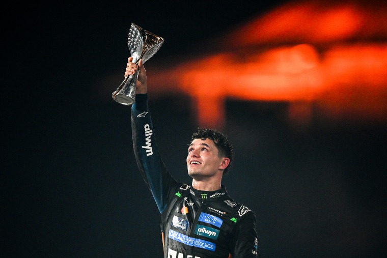 Lando Norris holds a trophy in the air