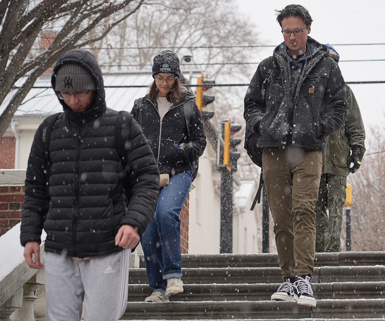 People walk down stairs in the snow as it falls outside