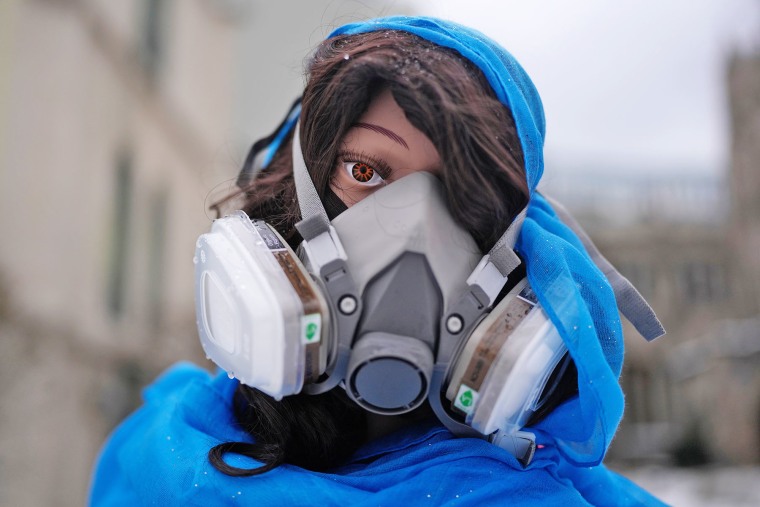 A mannequin representing the Mother Mary wears a gas mask in a nativity scene