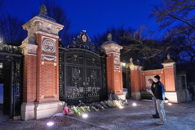 Visitors pause at a makeshift memorial at the Van Wickle Gate at Brown University