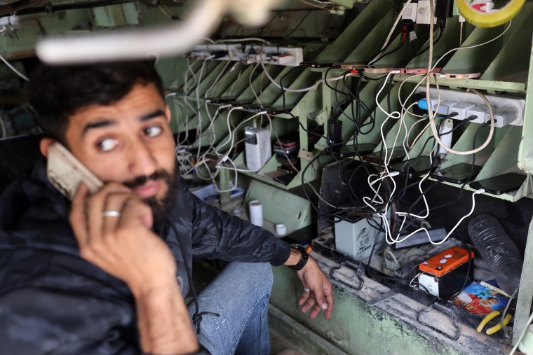 Yahya Akhrayiq, 27, uses a modified Israeli military vehicle abandoned by the Israeli army as a charging point for mobile phones and laptop computers in Gaza City on Nov. 29, 2025.