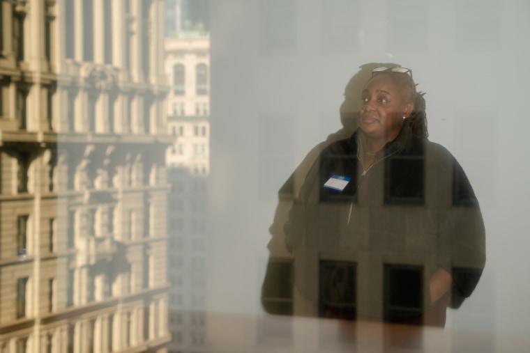 April Rose stands for a photo through a window, a reflection of a building can be seen overlayed
