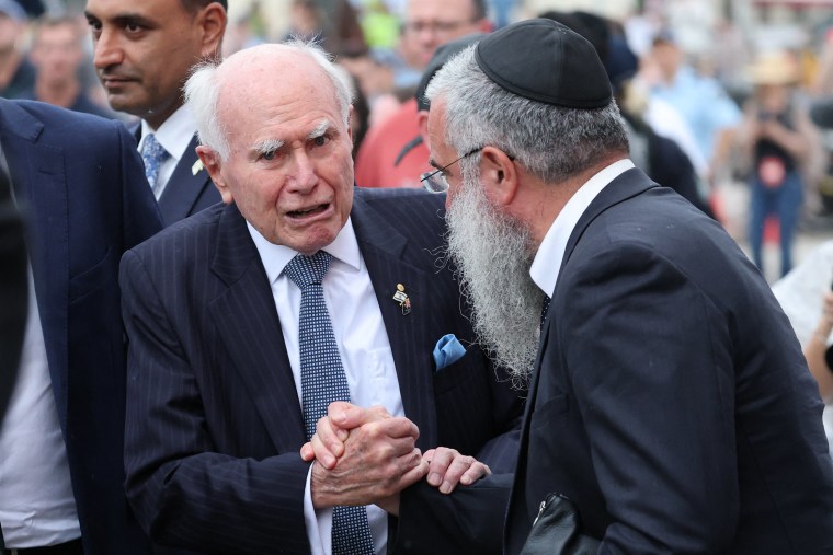 O ex-primeiro-ministro australiano John Howard aperta a mão de um rabino quando ele chega para participar de um serviço memorial em 21 de dezembro.
