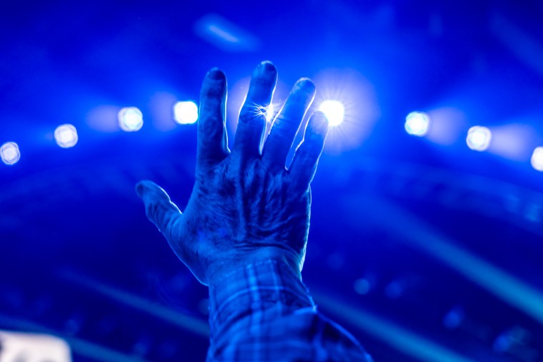 A raised hand in the air, covered in blue light