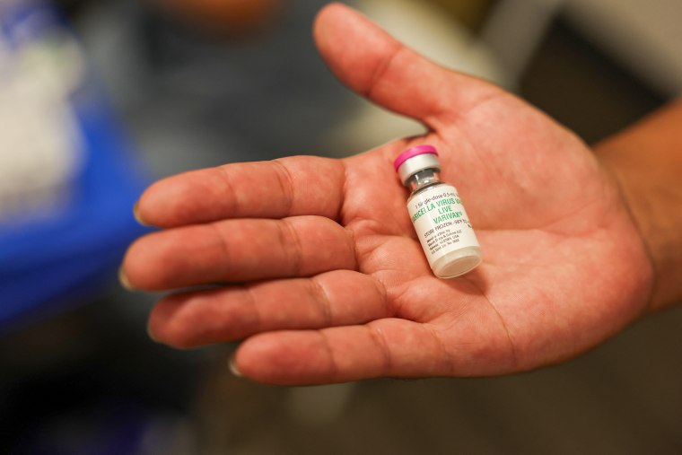 A man holds a bottle of Varivax vaccine.