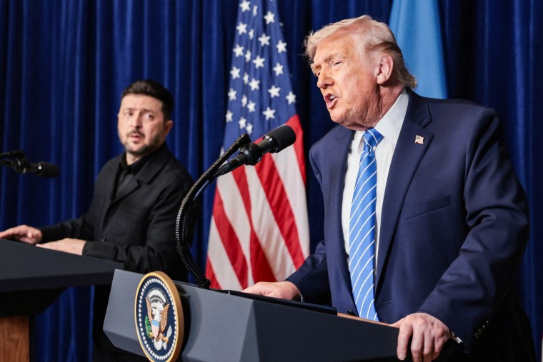 Volodymyr Zelenskyy, left, stands on a podium on stage next to Dondald Trump, who speaks at a podium beside him