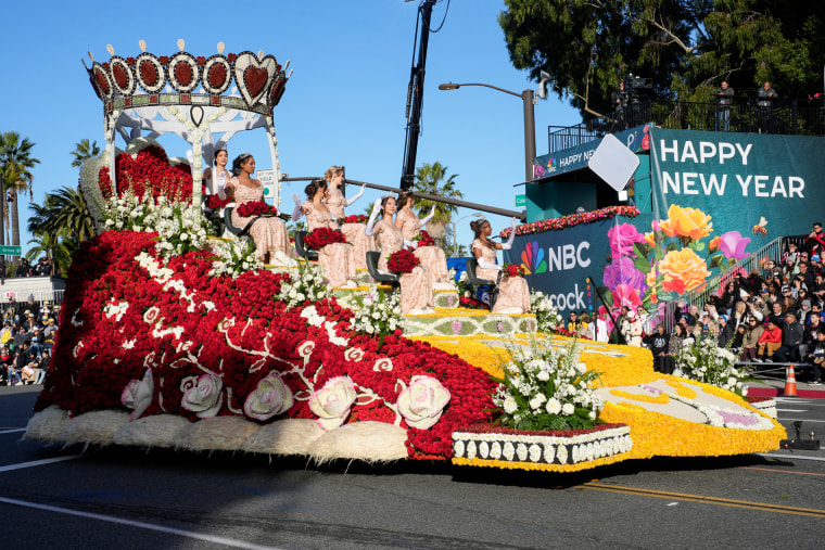 People in dresses sit on a float made of roses with a crown at the top
