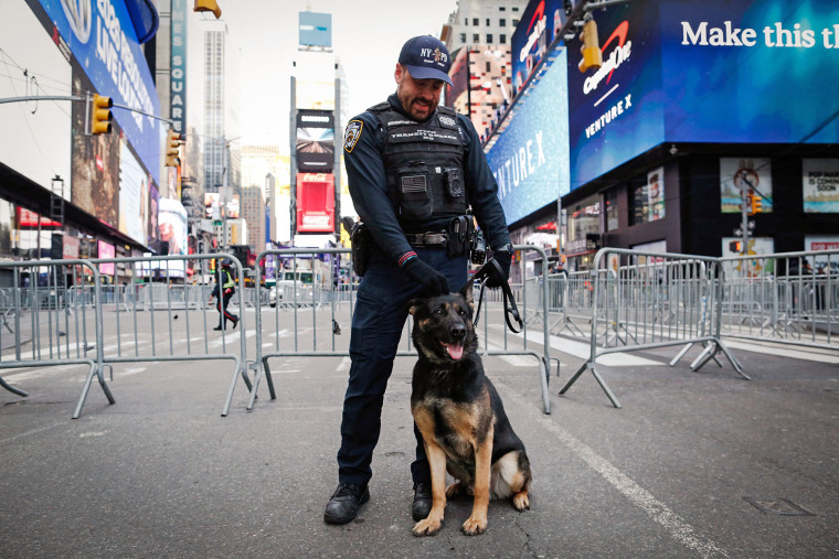 A police officer and dog stand watch in Times Square ahead of New Year's Eve celebrations on Dec. 31, 2025.