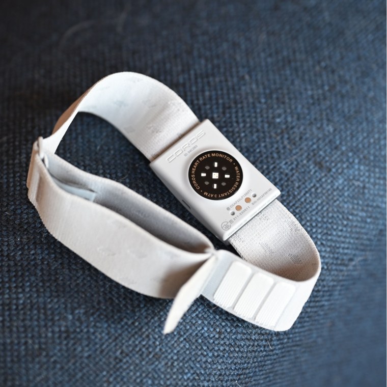 A close-up of the Coros Heart Rate Monitor resting on a blue fabric cushion.