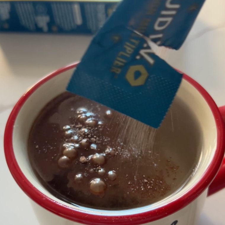 Woman pouring a Liquid IV hot chocolate packet into a mug