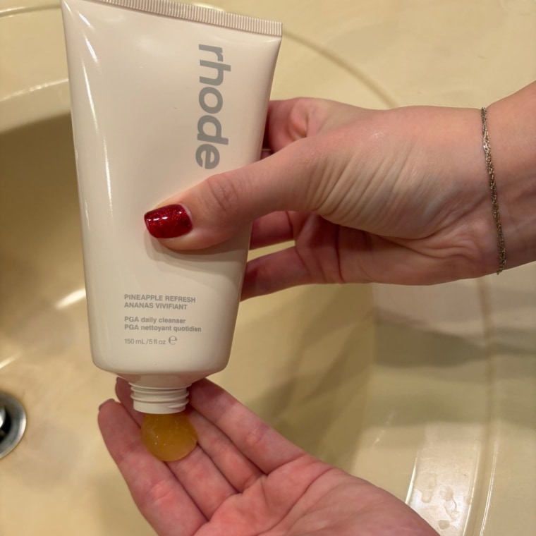 Woman dispensing Rhode cleanser on her hand