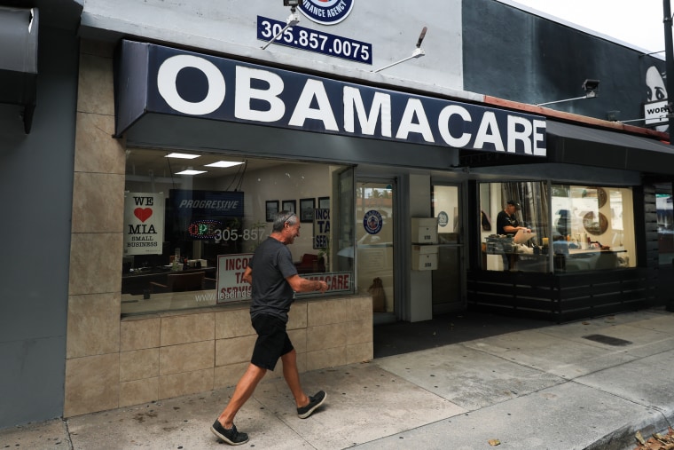 A person walks by a shop for Obamacare insurance