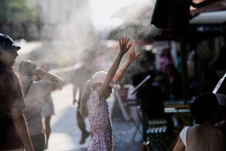 A child refreshes in front of a nebulizer outside, water is sprayed from above into mist