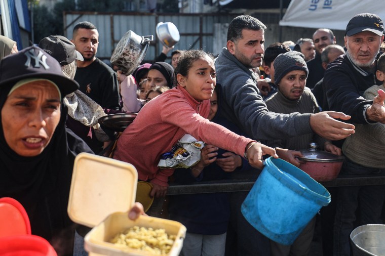 Displaced Palestinians gather to receive food aid in the Nuseirat refugee, central Gaza in December.