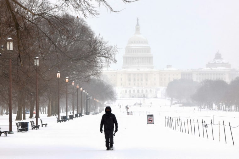 Seorang pria berjalan di sepanjang National Mall saat salju turun di Washington, DC.