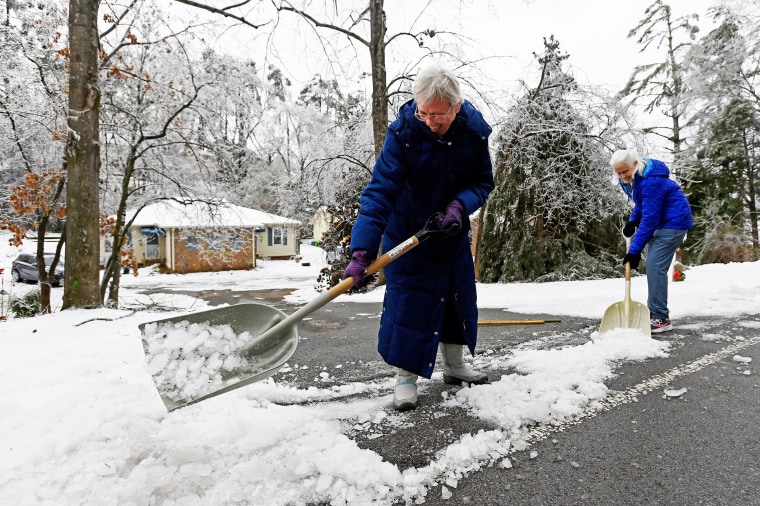 Terri Griffith, 68, left, and her friend Mary Ward, 71, shovel ice off their driveway.