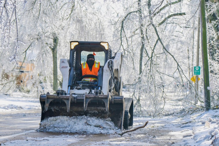 A worker clears a street of debris and ice in Mississippi.