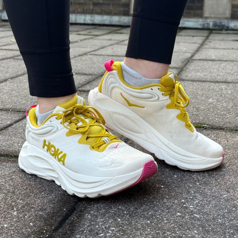 A person wearing a pair of yellow Hoka Gaviota 6 women’s running sneakers.