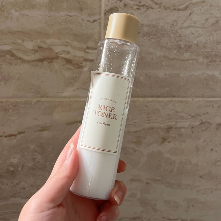 Woman holding toner bottle against tile background