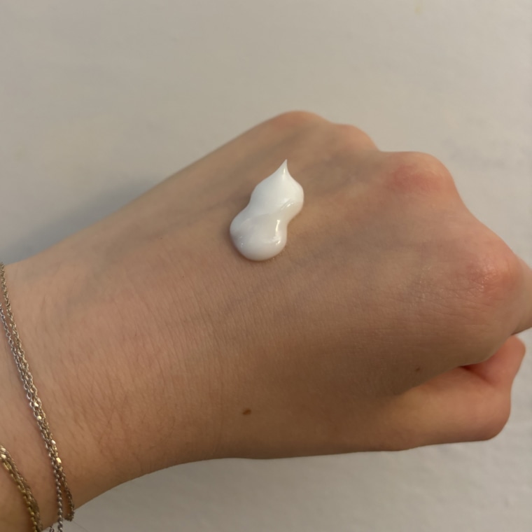 Quarter-sized amount of moisturizer on the back of woman’s hand.