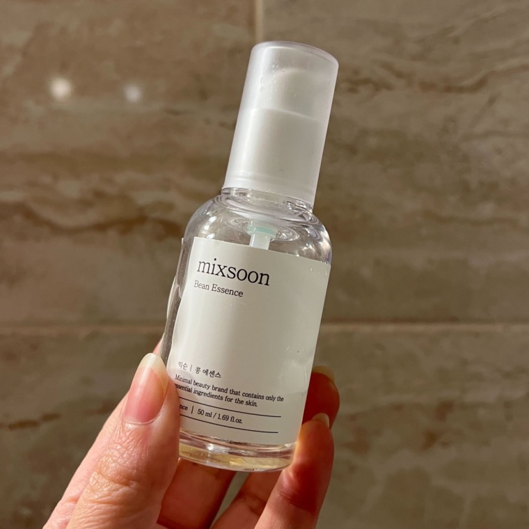 Woman holding serum bottle against a tile background