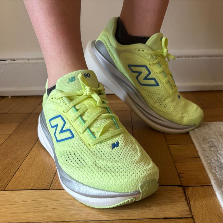 A person wearing a pair of yellow New Balance 1080v15 women’s running sneakers.