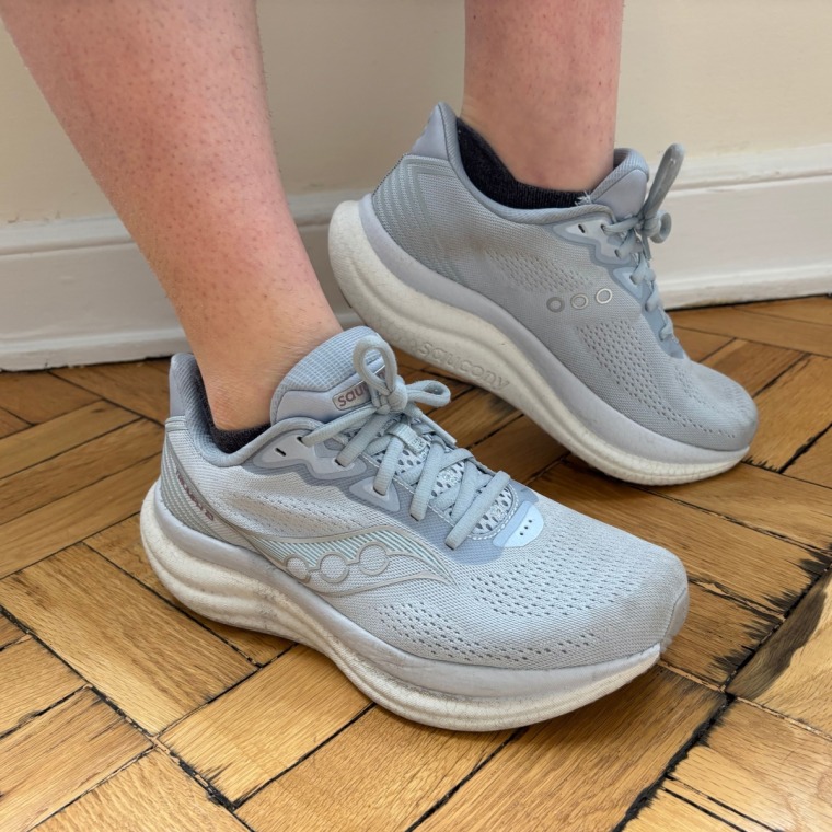 A person wearing a pair of blue Saucony Triumph 23 women’s running sneakers.