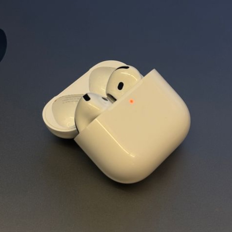 A pair of Apple AirPods 4 sitting on a table with the case open.