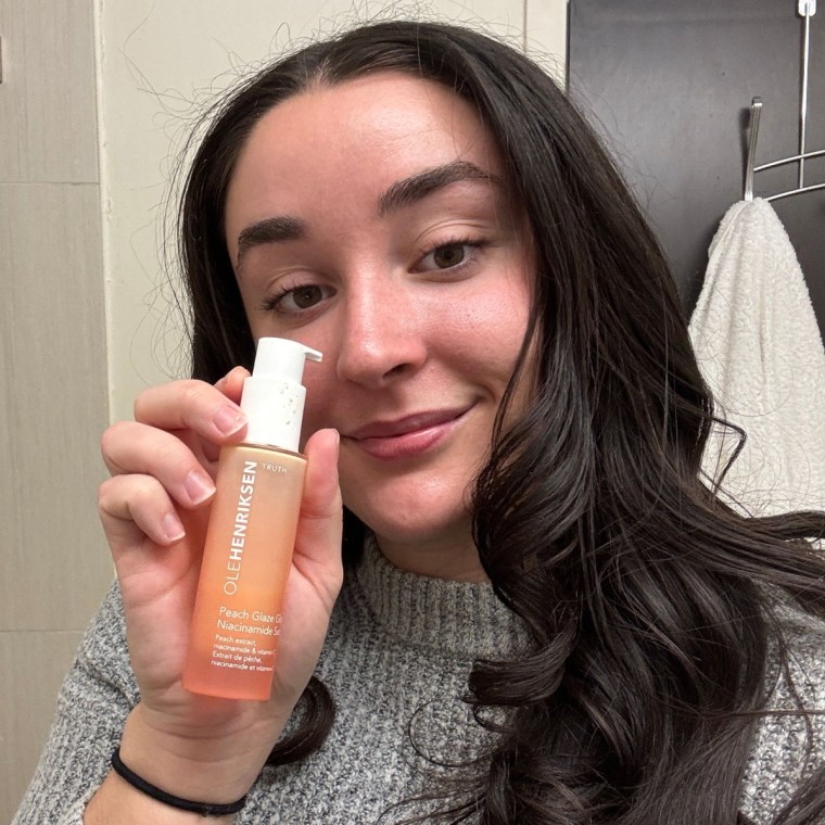 Person standing in bathroom applying a skin care product.