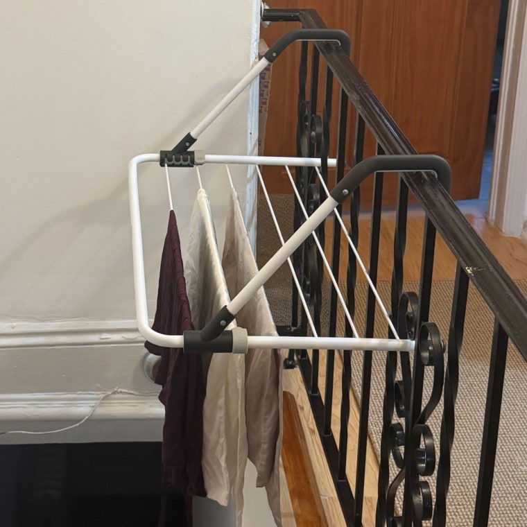 The Brabantia Drying Rack hanging off of a handrail OR The Brabantia Drying Rack folded and held against a wall