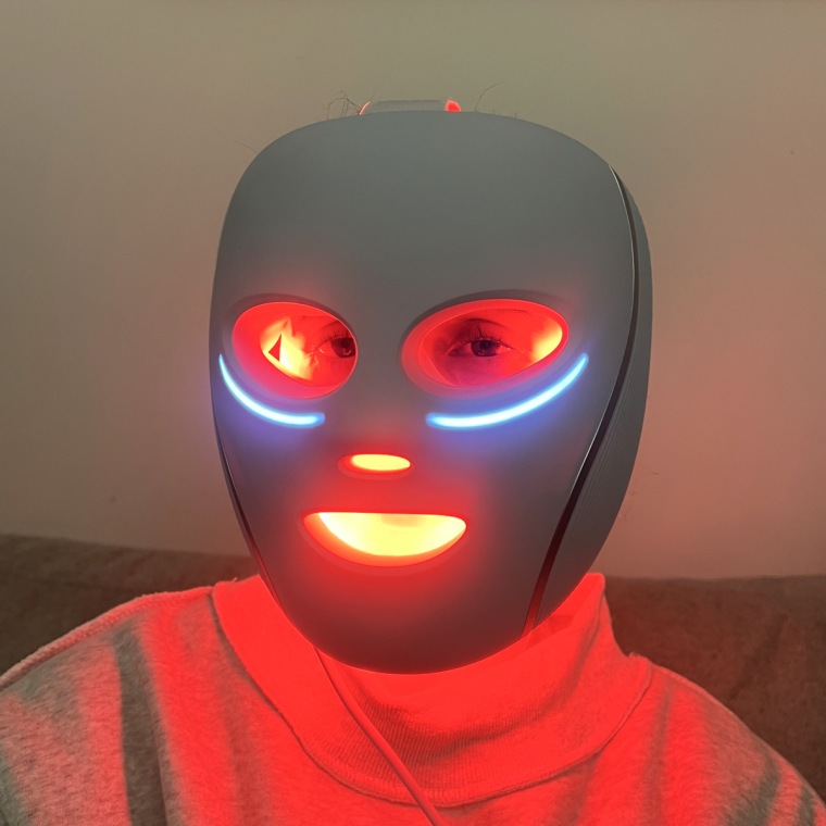 A close up of Godio wearing the Shark CryoGlow LED Face Mask. The lights emit a bright red glow from the eye, nose, and mouth cutouts.
