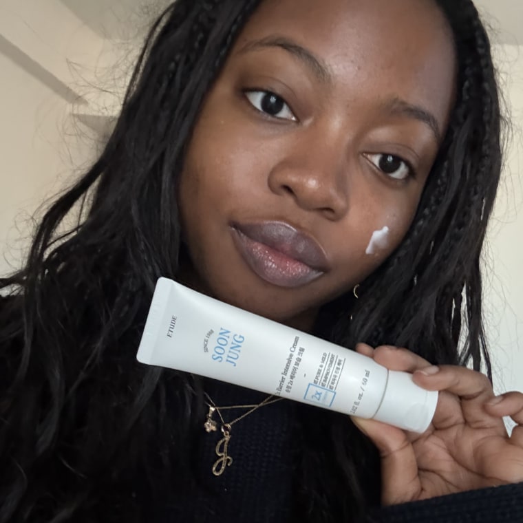 Alabi applying the Soonjung 2x Barrier Intensive Cream to her cheek in a bedroom.