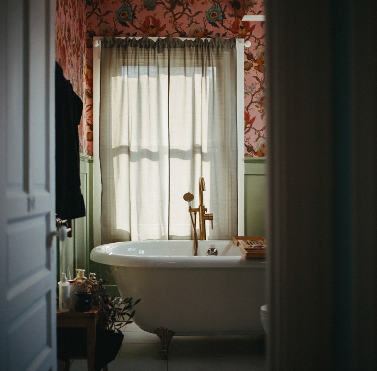 A bathtub and window can be seen from a doorway