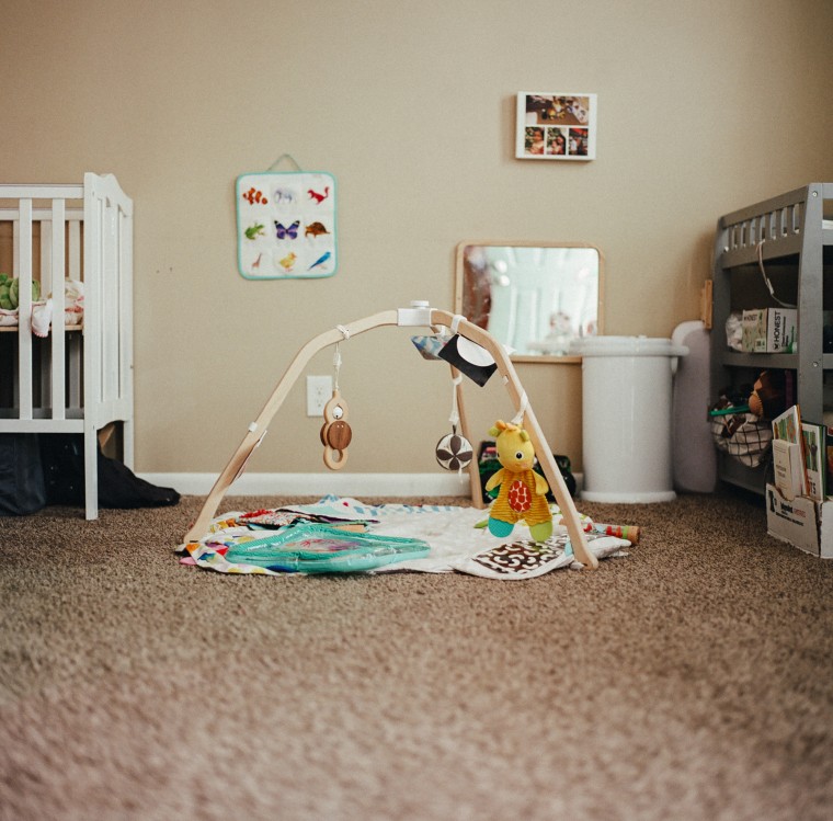 Baby toys and a blanket can be seen on the carpeted floor of a baby's bedroom