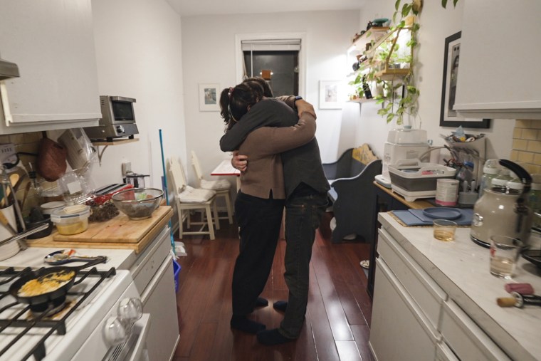 Val Calderon and her husband, Chris Russell, embrace at home in their kitchen.