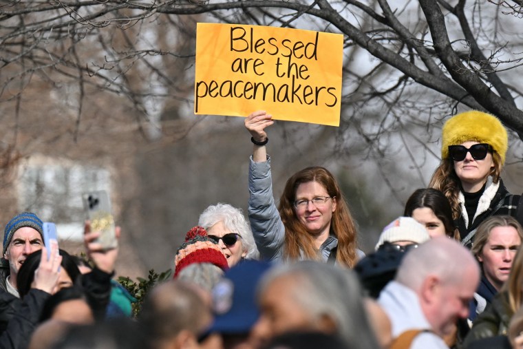 A woman holds a sign as Buddhist monks arrive at the Washington National Cathedral in Washington, DC.