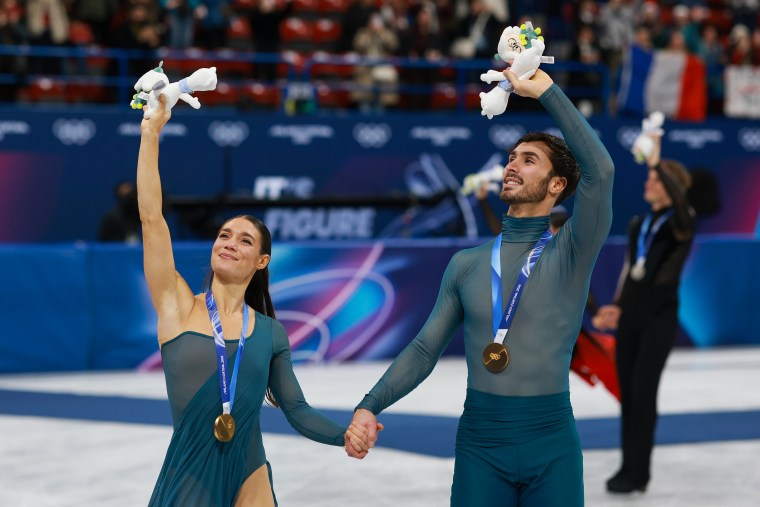 Laurence Fournier Beaudry e o parceiro da equipe francesa Guillaume Cizeron cumprimentam a multidão após a cerimônia de medalhas na Dança no Gelo