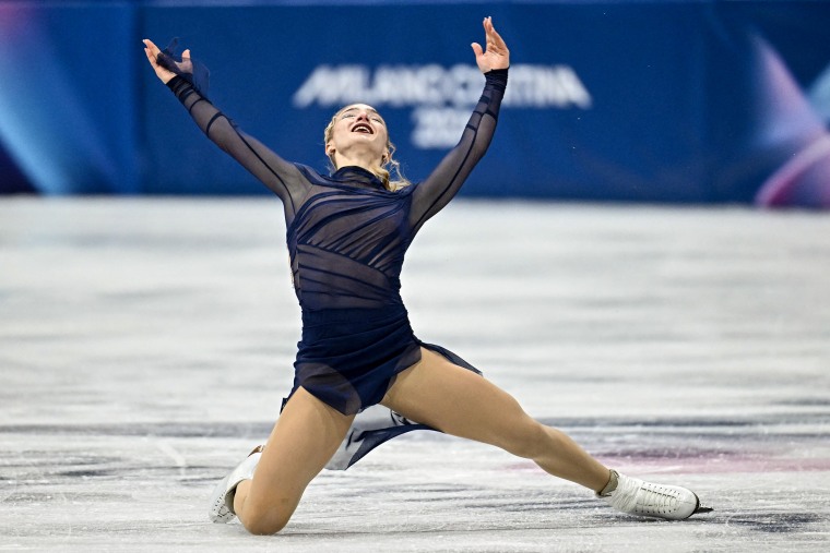 Amber Glenn lifts her hands toward the sky as she kneels on the ice after finishing a skating routine.