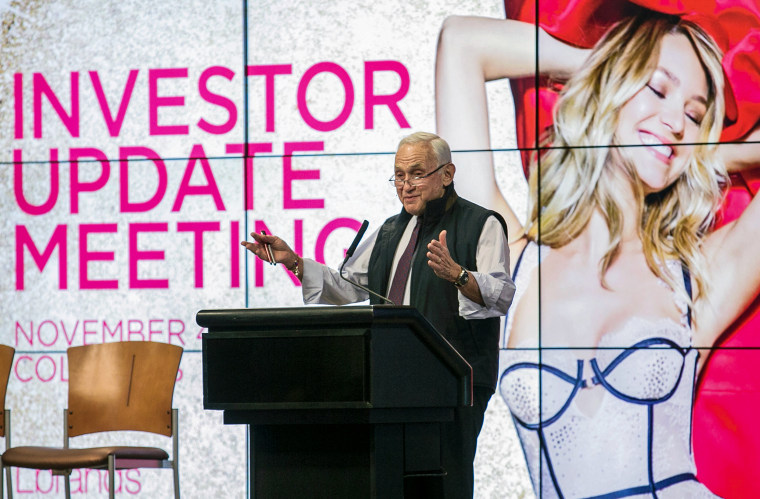 Les Wexner speaks at a lectern in front of a projection of a smiling woman wearing lingerie.