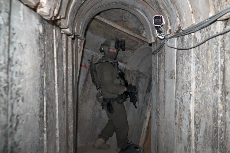 Image: An IDF soldier in full uniform, carrying a gun inside one of the tunnels.