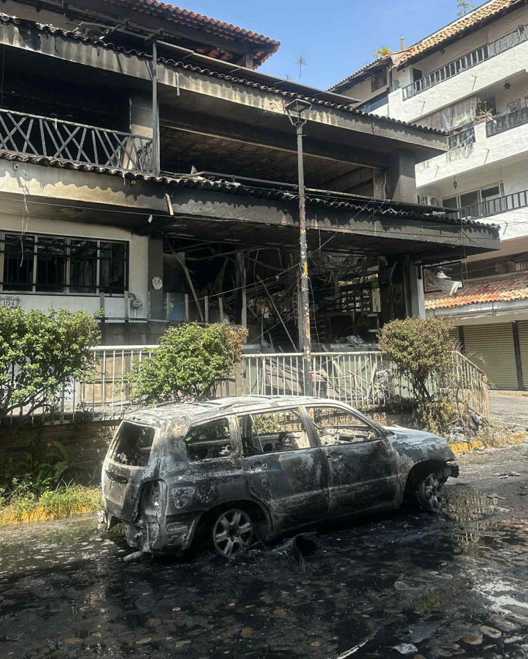 A burnt vehicle is seen outside in front of a burnt building