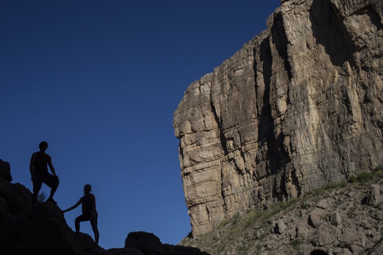 Tourists pose for photos on the banks of the Rio Grande across from a cliff face that is Mexico, in Big Bend National Park in Texas.