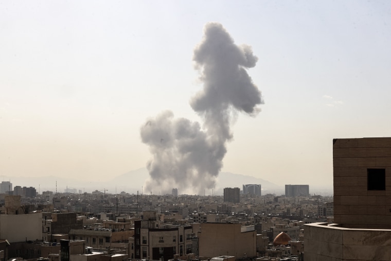 A large gray cloud of smoke rises over the skyline of Tehran.