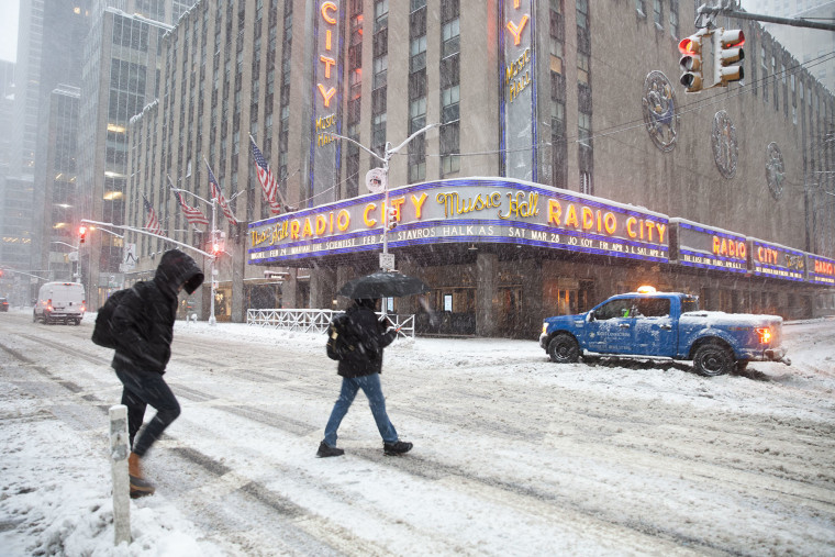 Pedestrians make their way through snow