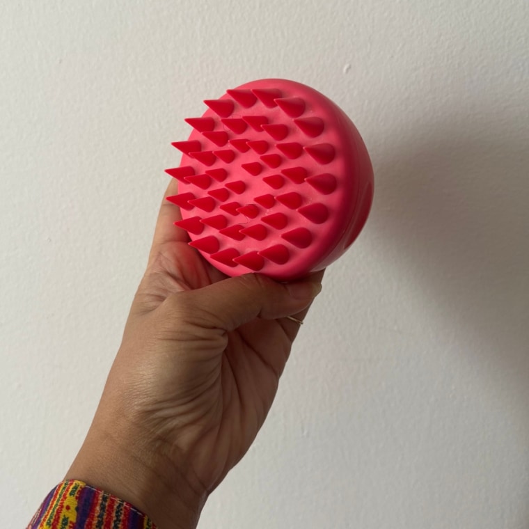 Woman holding pink scalp massager